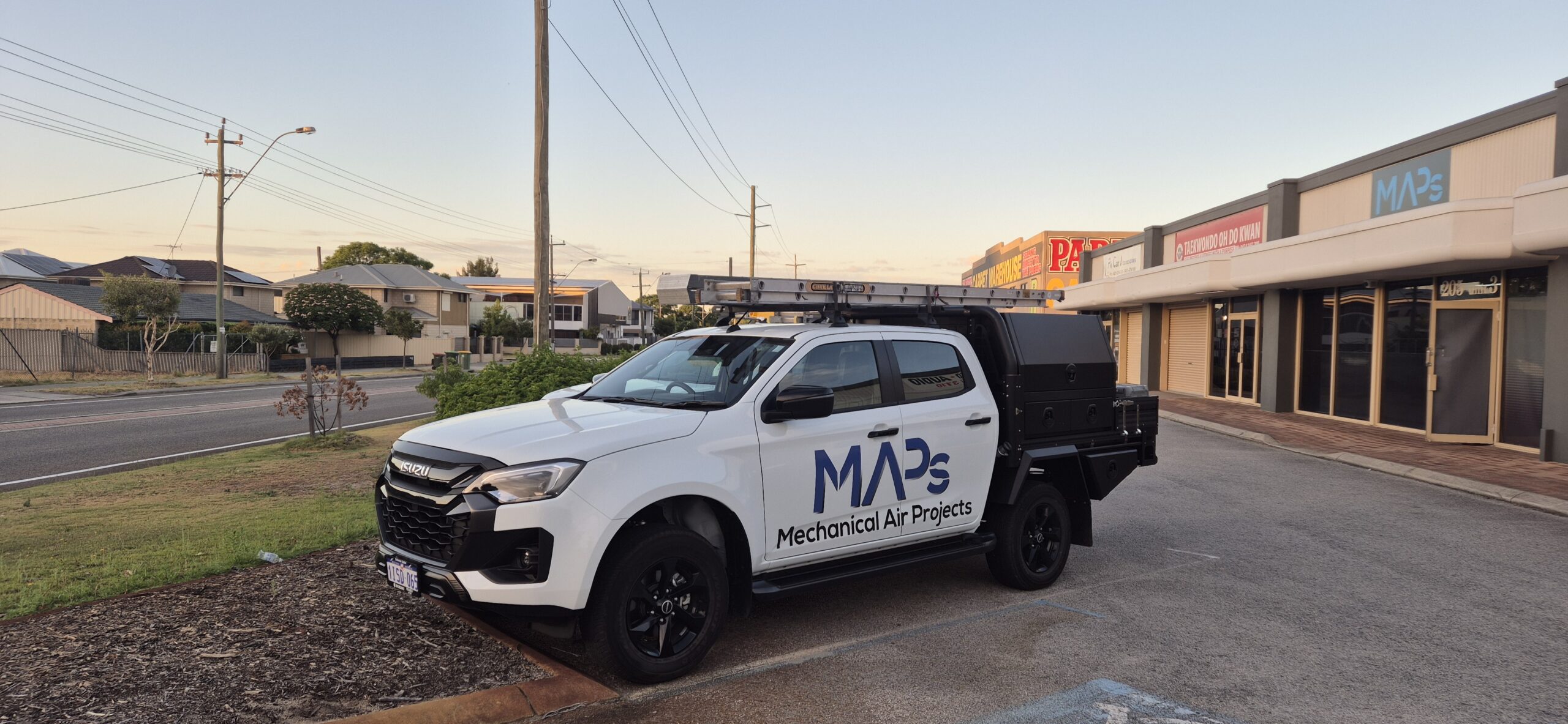 A white truck is parked outside a building displaying the MAPs electrical services logo