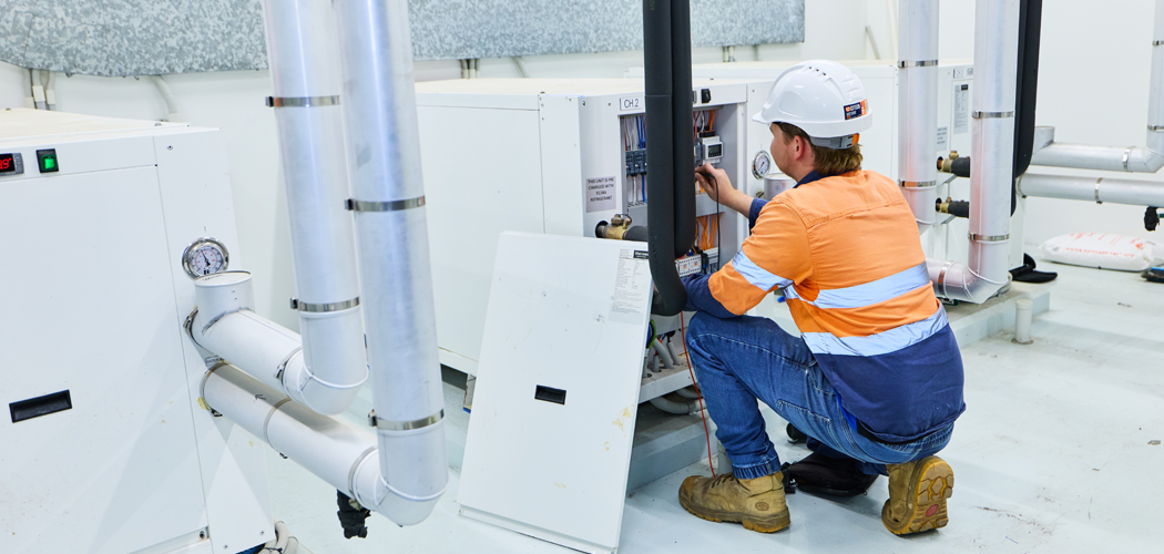 MAPs technician in an orange shirt and hard hat operates machinery, representing mechanical services subcontractor in Western Australia