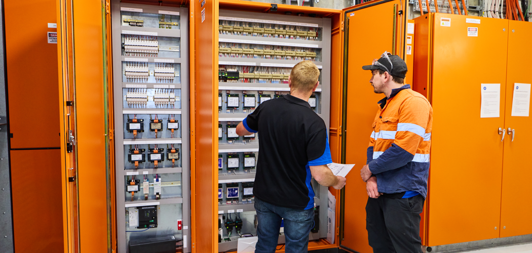 Two technicians inspecting a large electrical cabinet during commercial HVAC maintenance in Perth